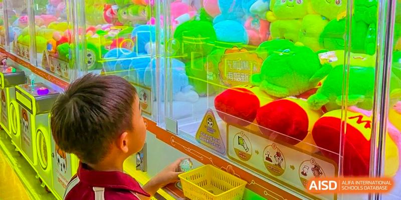 A student at Bromsgrove School Mission Hills playing a claw machine filled with colorful plush toys.