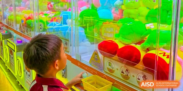 A student at Bromsgrove School Mission Hills playing a claw machine filled with colorful plush toys.