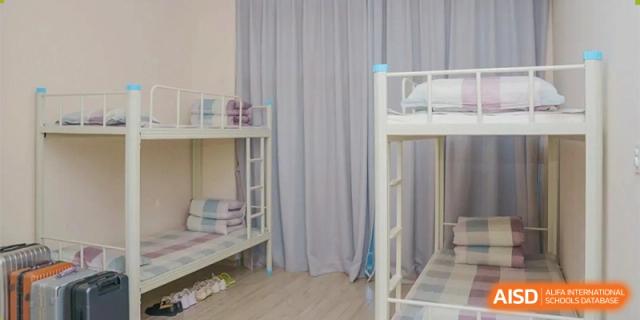 An empty bunk bed in a dormitory room at Bromsgrove School Mission Hills, with a privacy curtain partially drawn.
