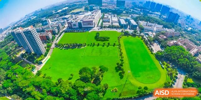 An aerial shot of Bromsgrove School Mission Hills' large green sports field and surrounding campus buildings.