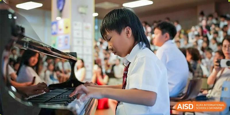 A male student in uniform playing the piano during a music recital at Bromsgrove School Mission Hills.
