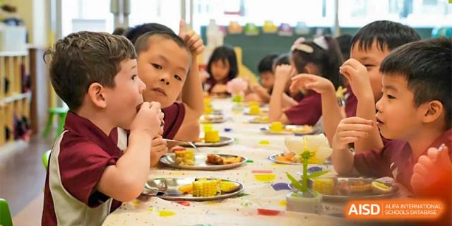 A group of Bromsgrove School Mission Hills students happily having lunch together at a table.
