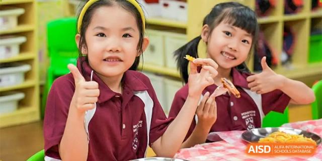 A close-up of a smiling female student at Bromsgrove School Mission Hills holding a french fry.