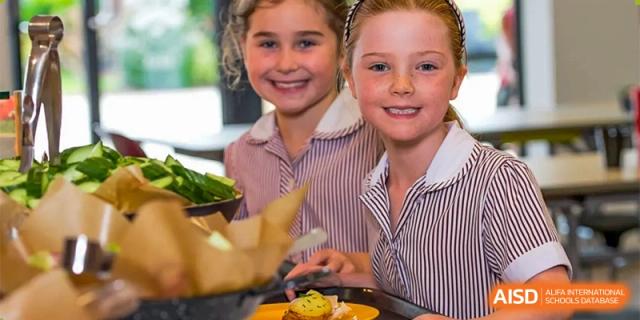 Two female students at Bromsgrove School Mission Hills smiling and looking at the camera during a meal.