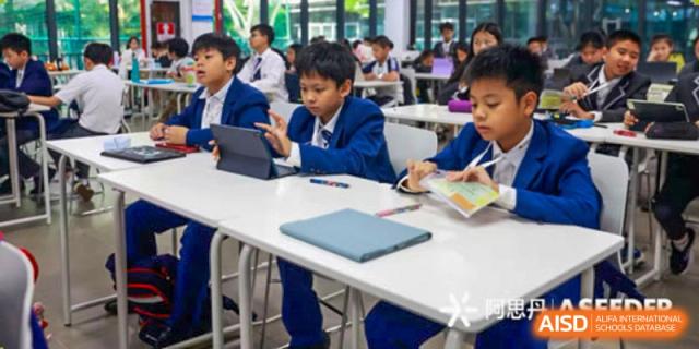 Harrow Lide High School Nanning students using digital tablets for learning while seated at a table in the classroom.