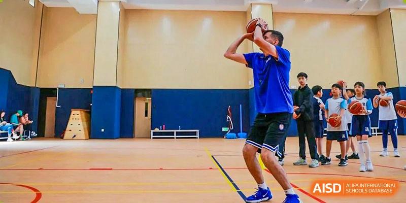 A male student mid-shot during an indoor basketball or sports practice, at Harrow Lide High School Nanning.