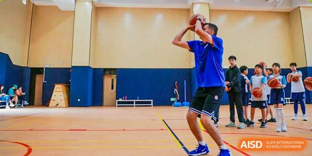 A male student mid-shot during an indoor basketball or sports practice, at Harrow Lide High School Nanning.