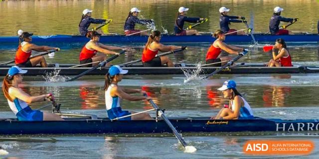 Rowers in a boat practicing on the water, with synchronized oars splashing, representing the rowing team of Harrow Lide High School Nanning.