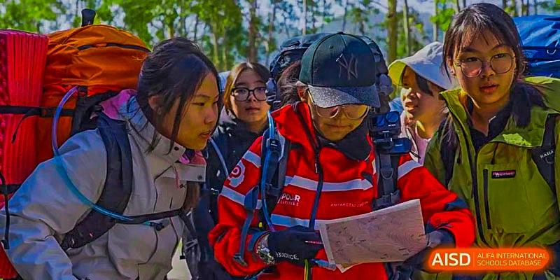A group of Harrow Lide High School Nanning students and staff reviewing a map during an outdoor field trip or activity.