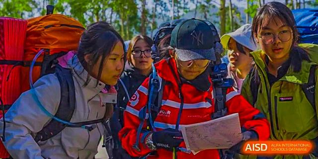 A group of Harrow Lide High School Nanning students and staff reviewing a map during an outdoor field trip or activity.