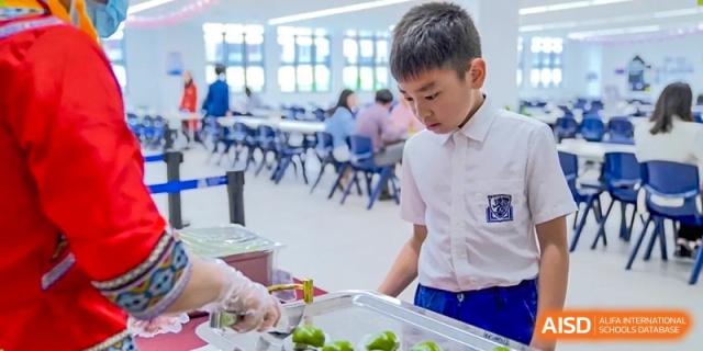 A student in uniform being served healthy food on a tray in the Harrow Lide High School Nanning lunch line.