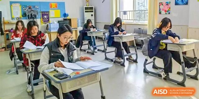 Students are diligently writing or taking an exam at individual desks in a bright classroom at Guokai International School of Qingdao.