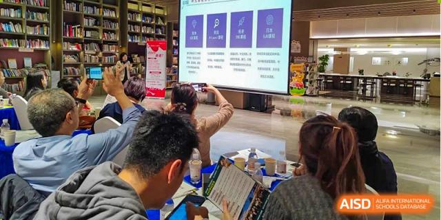Students are viewing a presentation on a screen displaying Chinese text and icons during an event or lesson at Guokai International School of Qingdao.
