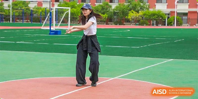 A female student jumps rope outdoors on a school track and field at Guokai International School of Qingdao.