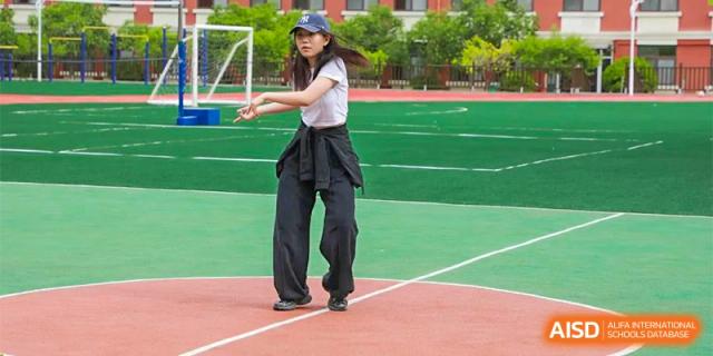 A female student jumps rope outdoors on a school track and field at Guokai International School of Qingdao.