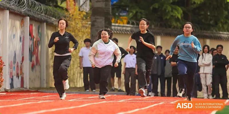 Students running on a track and field during an outdoor sports day or competition at Guokai International School of Qingdao.