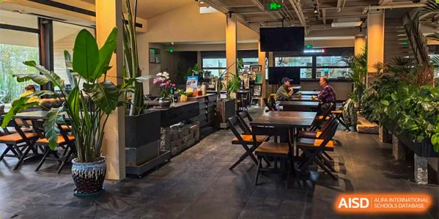 An interior view of a modern, stylish dining or common area with tables and chairs at Guokai International School of Qingdao.