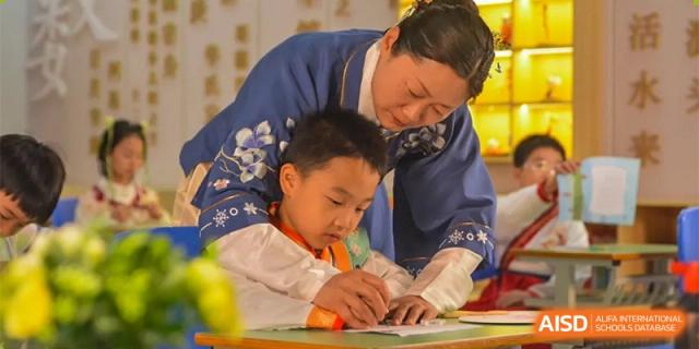 A woman in traditional attire is helping a young boy with his schoolwork at Chengdu Meishi International School.