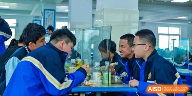 Students are looking at a blue parrot inside a glass cage at Chengdu Meishi International School.