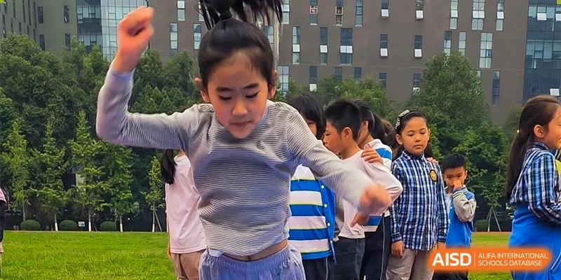 A young student from Chengdu Meishi International School is actively participating in a group activity outdoors, with a building in the background.