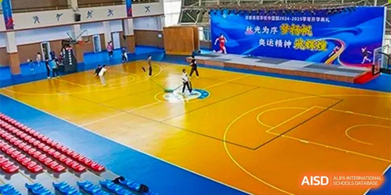 An indoor shot of students playing on a yellow basketball court with bleachers in the background at Chengdu Meishi International School.