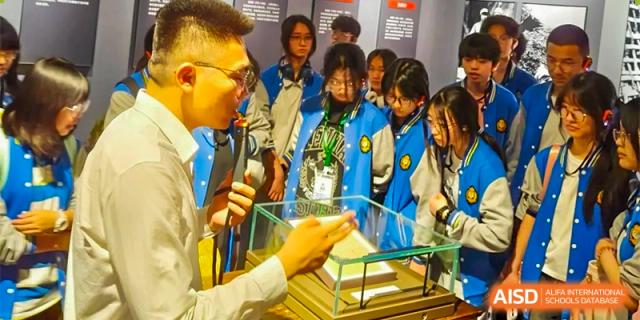 A group of students in blue jackets are reaching out to receive a certificate or award at Chengdu Meishi International School.