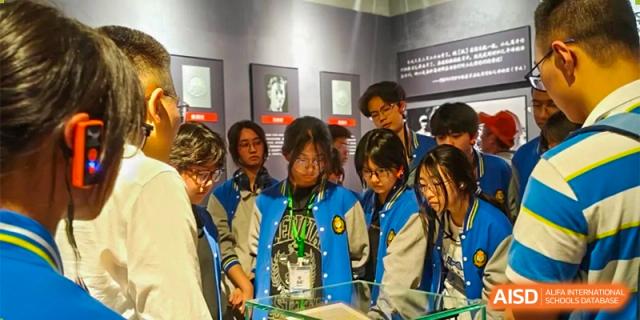 A group of male students in matching blue jackets are sitting together, watching an event at Chengdu Meishi International School.