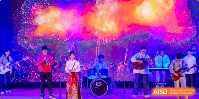 Two students are performing on a stage lit by colorful lights and fireworks at Chengdu Meishi International School.