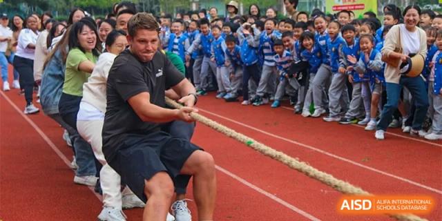 Students and a teacher are participating in a tug-of-war competition at Chengdu Meishi International School.