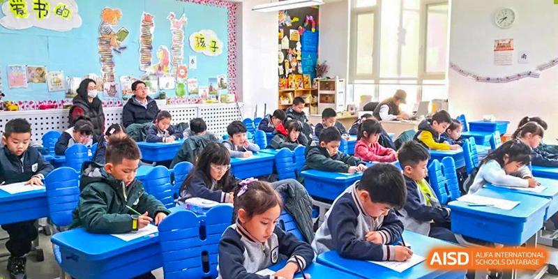 Young Qingdao Cornerstone Bilingual School students sitting at their desks and working on a class assignment.