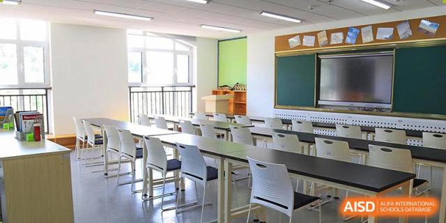 An empty classroom at Qingdao Cornerstone Bilingual School with desks and chairs neatly arranged.