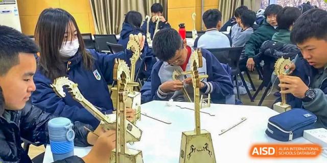 Qingdao Cornerstone Bilingual School students building a tall wooden structure as part of a class project.