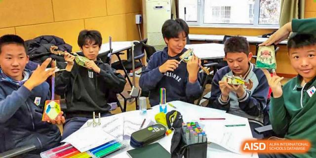 A group of Qingdao Cornerstone Bilingual School students collaborating on a project at a table.