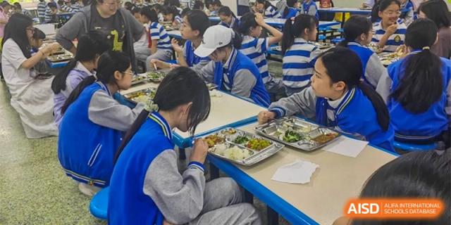 A student is eating at a table with other students at Chengdu Meishi International School.