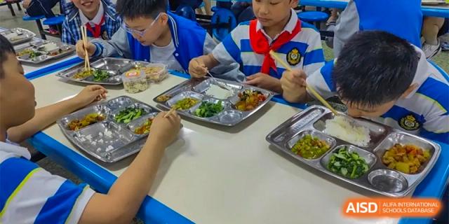 Two students are sharing a meal on a tray in the cafeteria at Chengdu Meishi International School.