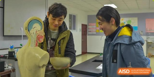 Two students are looking at a bowl of food in a dining area at Chengdu Meishi International School.