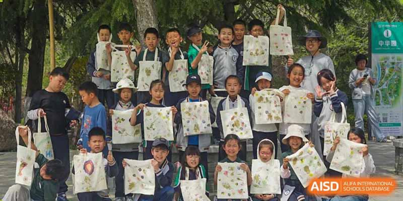 A large group of Qingdao Cornerstone Bilingual School students holding up their painted bags for a group photo.