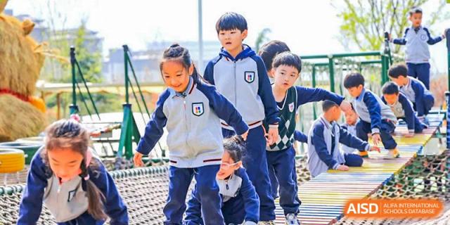 Qingdao Cornerstone Bilingual School students walking across a rope bridge on the school playground.