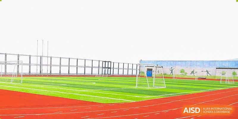 The outdoor sports field at Qingdao Cornerstone Bilingual School with a running track and a soccer goal.