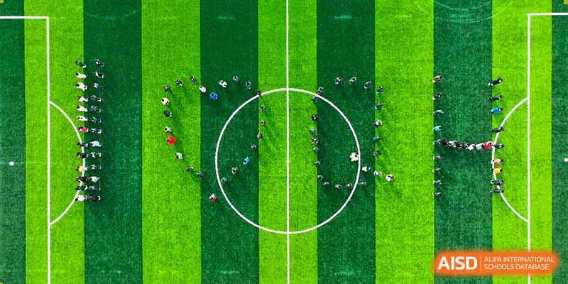 An aerial view of Qingdao Cornerstone Bilingual School students gathered in a circular formation on a soccer field.
