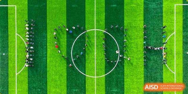 An aerial view of Qingdao Cornerstone Bilingual School students gathered in a circular formation on a soccer field.