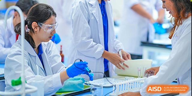 A close-up shot of a teacher or student from Tsinglan School wearing a lab coat and blue gloves while working on a project.