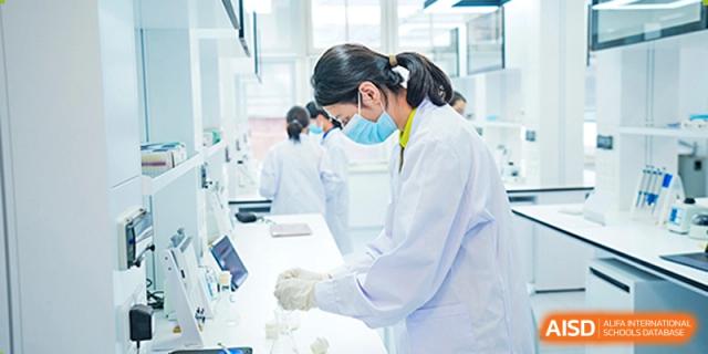 A female teacher or staff member from Tsinglan School wearing a lab coat and gloves while working in a lab.