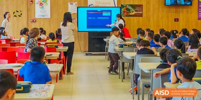 A group of students from Tsinglan School looking at a screen in a classroom while a teacher stands nearby.