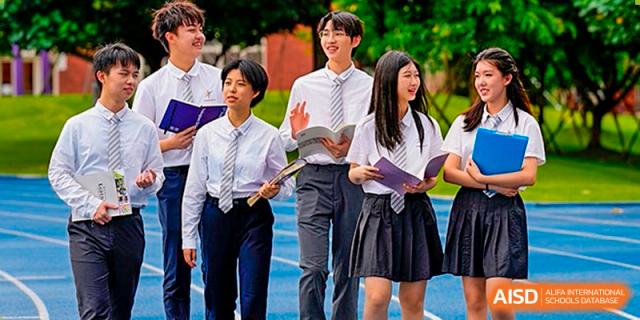 A group of students from Tsinglan School, dressed in uniforms, walk and talk outside on a sunny day.