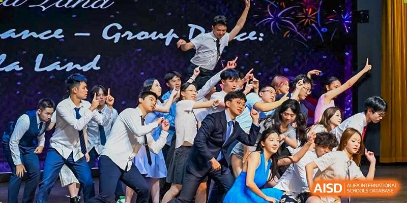 A group of students from Tsinglan School performs a choreographed dance on a stage with bright lights.