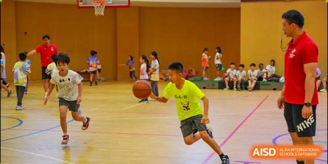 A student from Tsinglan School dribbles a basketball on an indoor court during practice.