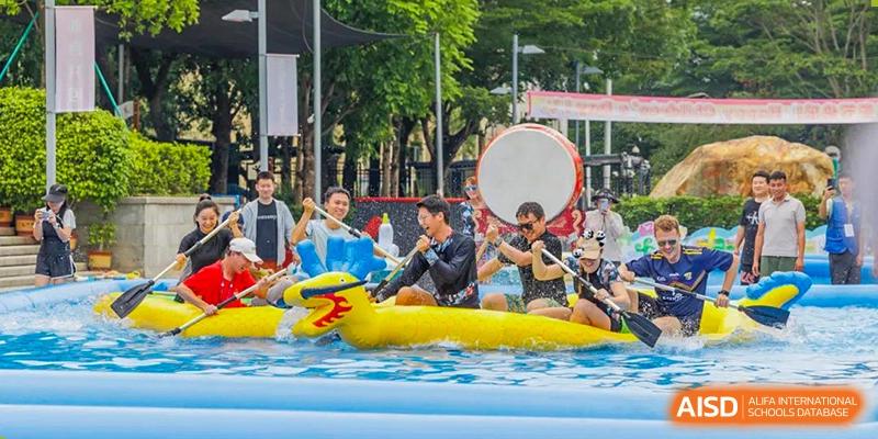 Students and teachers from Tsinglan School participating in a dragon boat race in an inflatable pool.