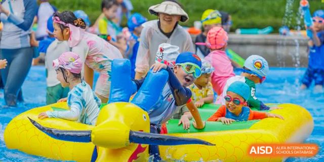 Students from Tsinglan School playing on a yellow inflatable playground on a sunny day.