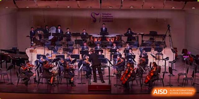 A wide shot of an orchestra from Tsinglan School performing on a stage.